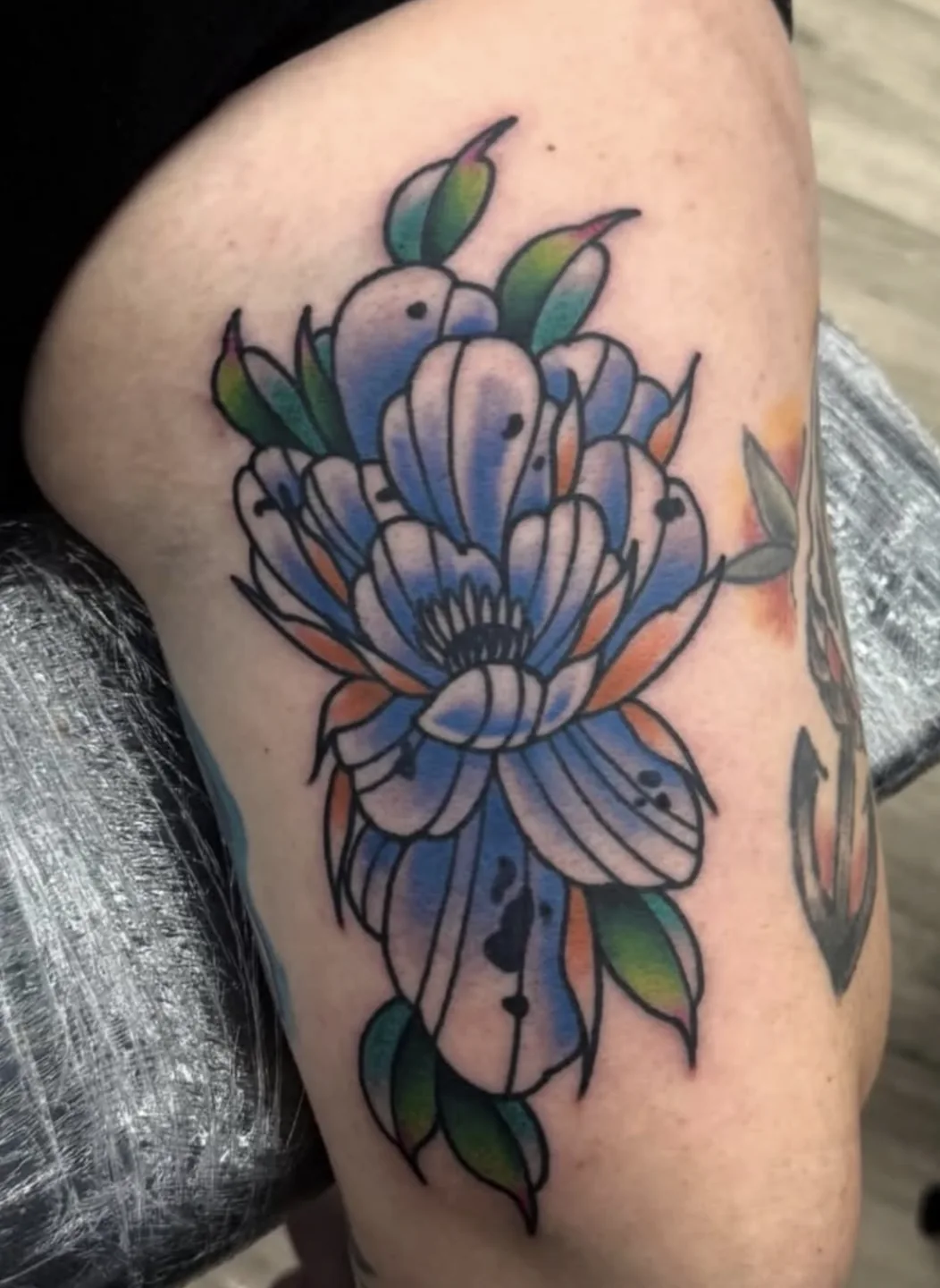 Colorful flower tattoo with blue petals on leg