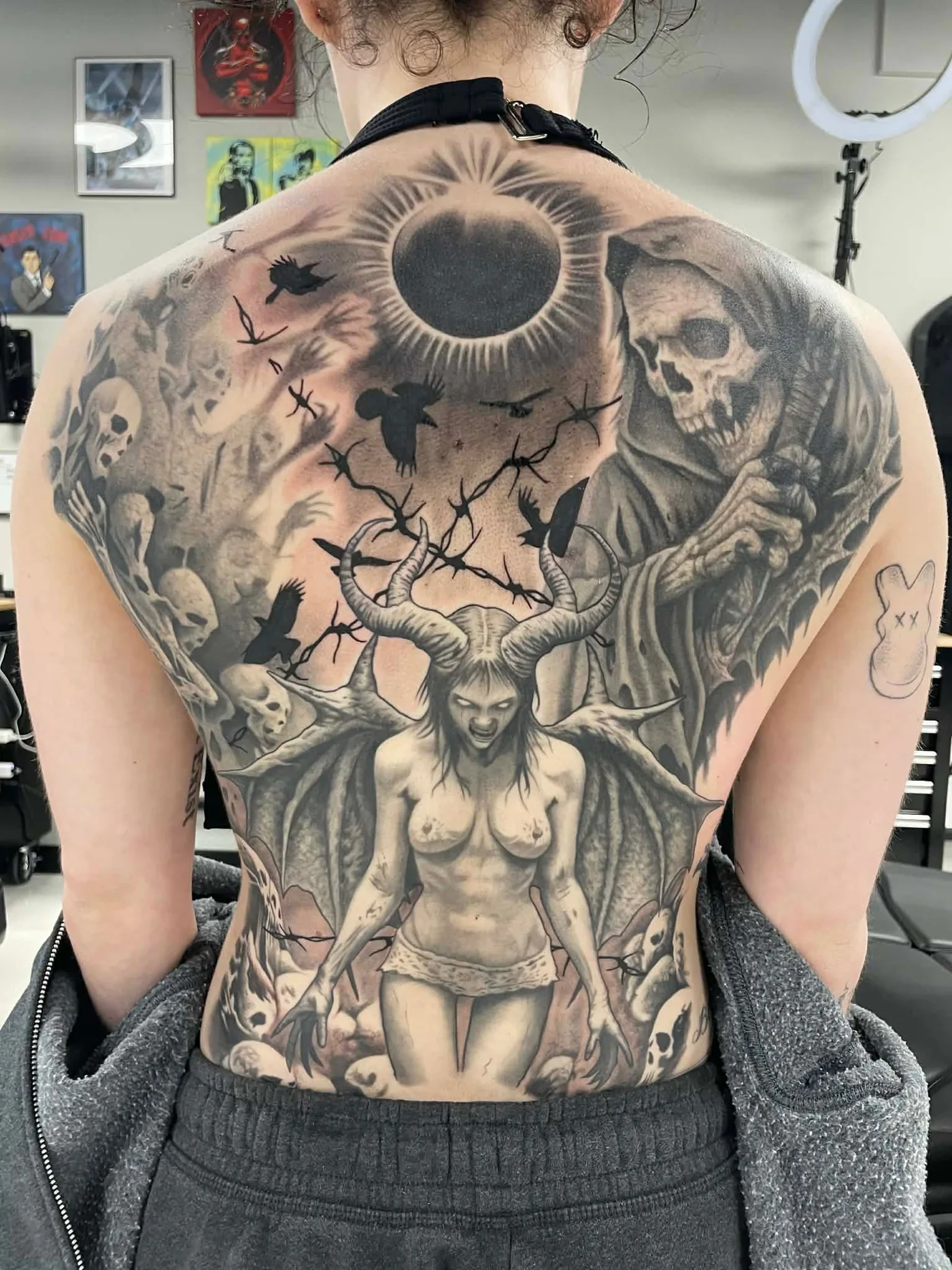 Large black and grey back piece with demonic figure, skulls, and grim reaper