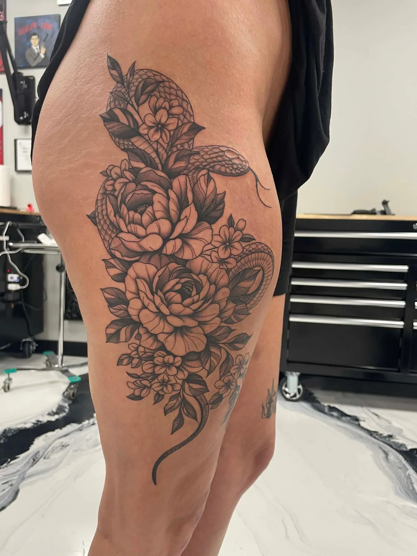 Black and grey snake and flowers tattoo on thigh