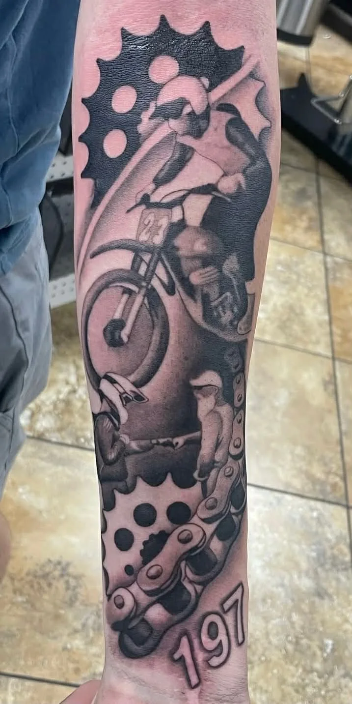 Motocross rider, gears, and chain tattoo on arm